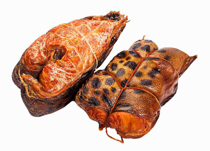 Зубатка горячего копчения - это уникальная по сочетанию вкусовых и полезных качеств рыба. Она обладает нежным белым мясом, полностью лишенным мелких костных тканей, поэтому её можно смело давать детям. Её часто включают в меню дошкольных учреждений.  Как и все обитатели океанов, эта рыба насыщена полезными витаминами и минералами. Йод, цинк, железо, марганец - это лишь малая толика тех богатств, что заложены природой в мясе зубатки горячего копчения. Рассыпчатая структура позволяет полностью ощутить нежнейший вкус и тонкий аромат зубатки. Но стоит отметить, что количество жиров в ней достаточно велико, так что покупая зубатку, помните, что она непременно скажется на вашей талии. Этот морской деликатес рекомендован к употреблению лицам, страдающим заболеваниями нервной системы, щитовидной железы, пищеварительного тракта. Так же зубатку горячего копчения включают в рацион людей с недостатком веса, так как она является природным источником животных жиров, так необходимых для роста и деления клеток организма.